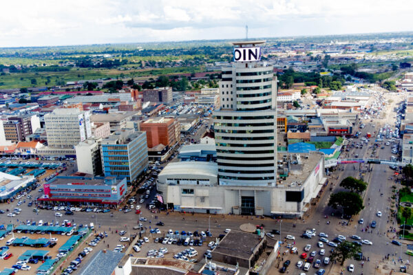 Comprehensive city-scale media project for Joina City, Harare. Wide-angle aerial drone shot capturing the iconic skyscraper and retail complex integrated into the city's central business district at sunset
