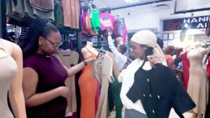 Lifestyle cinematography example: Two women shopping for apparel at Joina City during the Festive 2025 season. Features a bright, high-energy retail environment with colorful clothing displays and natural interactions