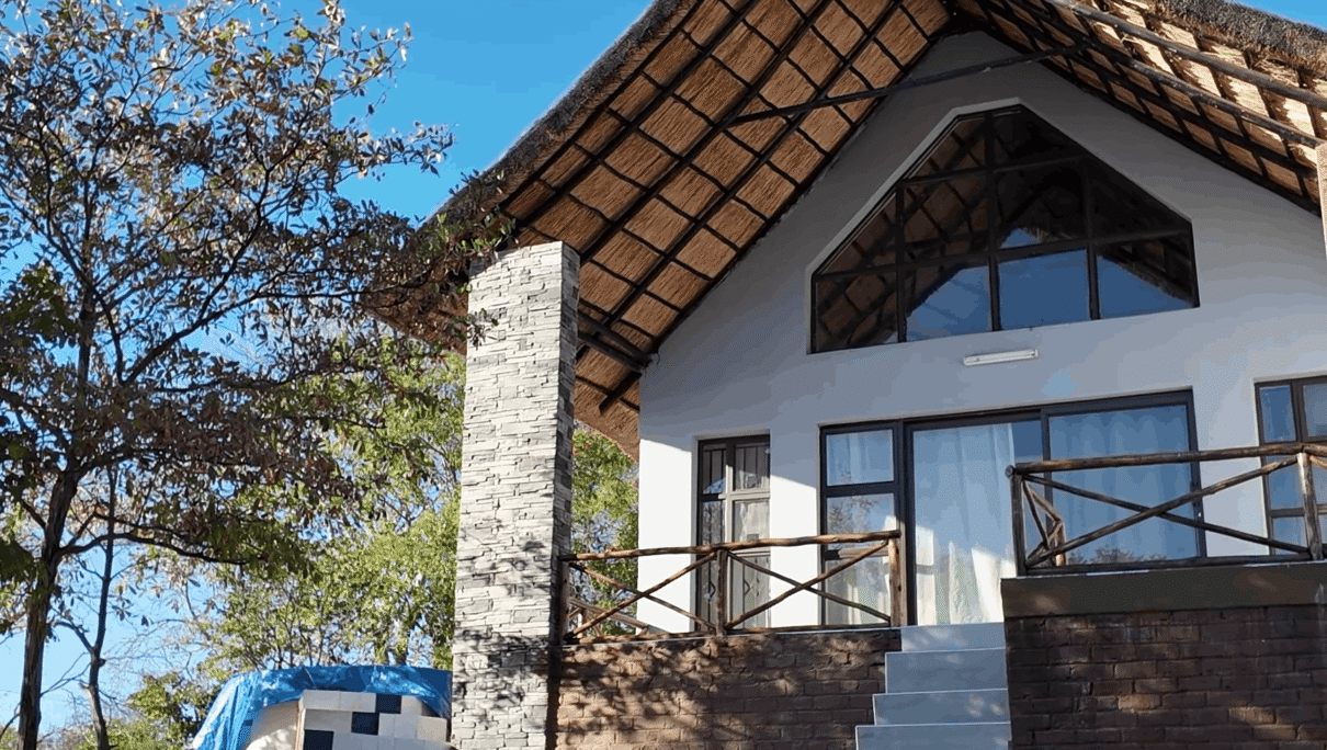 Video thumbnail for Sterling Kanyemba Resort featuring a luxury thatched-roof lodge nestled in a lush green forest. The sun reflects off a modern swimming pool in the foreground, highlighting high-end safari hospitality and architectural design.